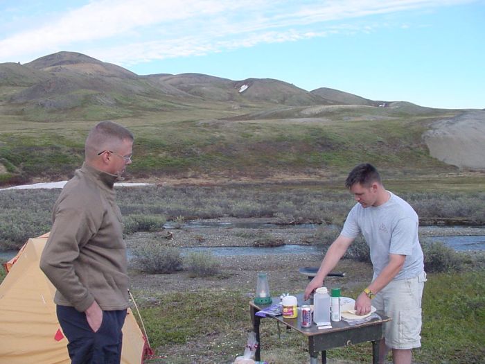 CW2 Gene Frazier watches SGT Wainwright prepare dinner in the field.