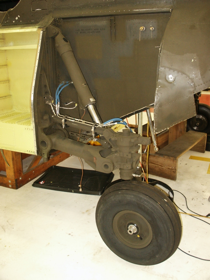 The left aft landing gear of CH-47D Chinook helicopter 85-24336 showing the ground proximity switch and air-oil (oleo) strut.