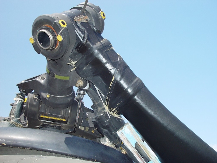 July 2002: This photograph shows extensive damage to the aft rotor system. A lead-lag dampner has broken off allowing the green blade to strike the fuselage and ground. All blades on a Chinook rotor system are color coded - Red, Green, or Yellow.  Look for the paint stripe on the rotor head - the green stripe is easily visible.