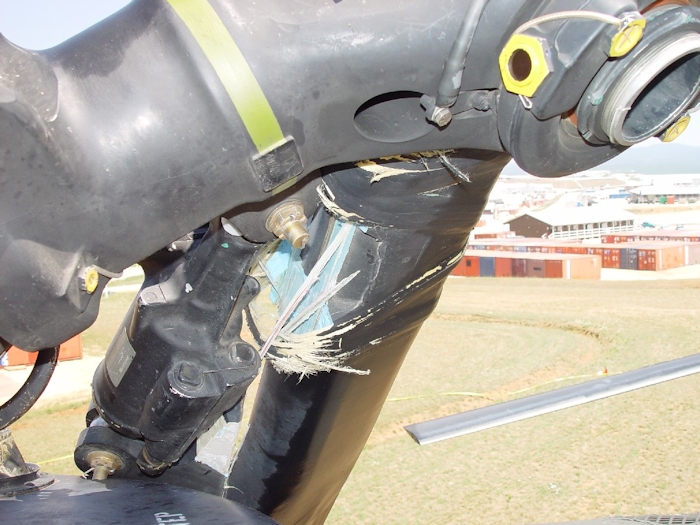 July 2002: This photograph shows extensive damage to the aft rotor system. A lead-lag dampner has broken off allowing the green blade to strike the fuselage and ground. All blades on a Chinook rotor system are color coded - Red, Green, or Yellow.  Look for the paint stripe on the rotor head - the green stripe is easily visible.