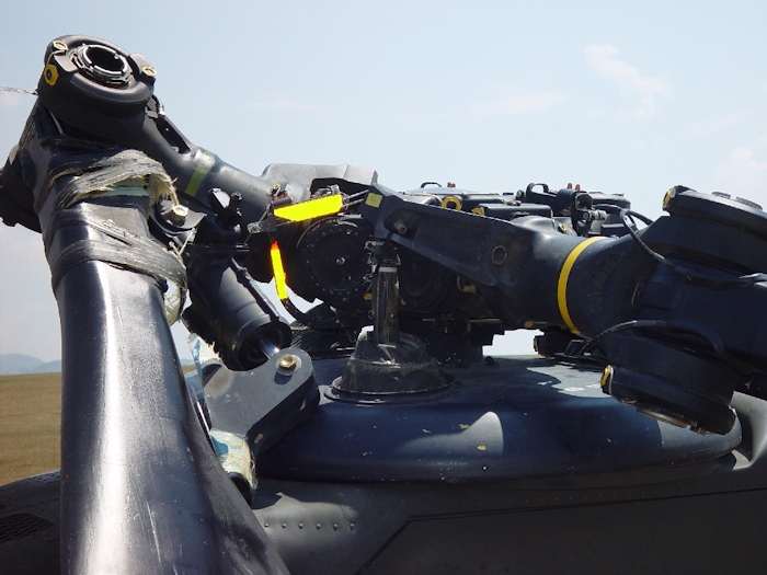 July 2002: Without the droop stops engaged and the dampner firmly attached, an aft rotor blade will make contact with the fuselage during engine shutdown and cause extensive damage. Here one can see the Kevlar Windings that are wrapped around the blade and dampner lug mount - they are now broken. Thousands and thousands of wraps of hair thin strands normally attach the two items together creating an extremely strong bond capable of withstanding the extreme loads imposed during flight operations.