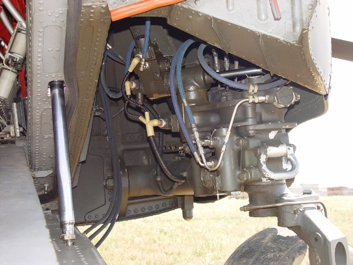 July 2002: A view inside the wheel well for the right aft landing gear. It houses the power steering module that drives the right aft gear so the aircrew can four wheel taxi a Chinook in a manner similar to driving an automobile. The power steering module is the item that has the long shiny, steel colored shaft protruding from a hydraulic actuator.