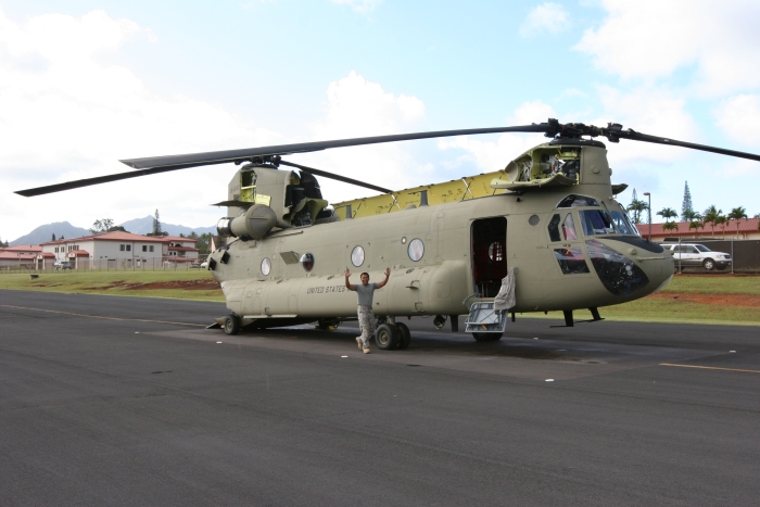 10 December 2011: SGT Josh Pastor, Flight Engineer, waves to the camera as he walks past CH-47F Chinook helicopter 08-08767 resting on the Army National Guard ramp at Wheeler Army Airfield, Oahu, Hawaii. 08-08767 was transferred to Company B - "Voyagers", 171st Aviation, in late November and utilized by members of the S3 Incorporated New Equipment Training Team (NETT) to support the aircraft qualification of unit aircrew members.