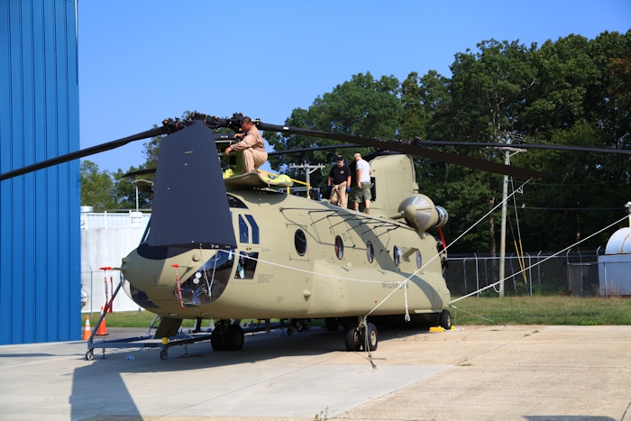 11 September 2013: CH-47F Chinook helicopter 12-08106 rests on the ramp at the Boeing Millville facility, Millville Municipal Airport (KMIV), New Jersey, awaiting movement to the Port of Baltimore for ship transport to the Republic of Korea. CH-47F New Equipment Training Team (NETT) Maintenance Test Pilot Rich Felter preflights the forward pylon as Standardization Instructor Bill Cagle closes up the top. The fellow in the shorts is unknown.