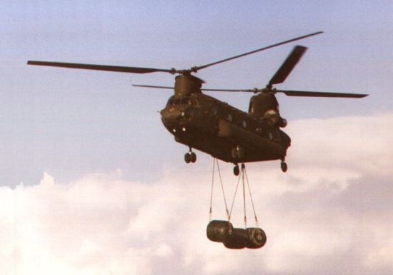 A Chinook assigned to the 205th Assault Support Helicopter Company (ASHC) "Geronimos" transports fuel blivets at Finthen Army Airfield, West Germany, circa 1987. If you can read this, you are too close.