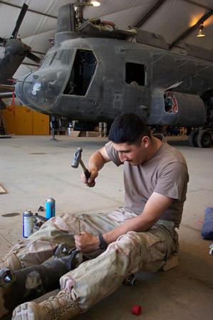 Helicopter mechanic PFC Ramon Martinez of McAllen, Texas, works on the landing gear of an U.S. Army CH-47D Chinook.