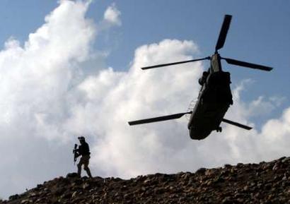 A U.S. soldier secures the area as a Chinook helicopter flies over in Jegdelic village, about 90 km southwest of Kabul on 24 December 2004. About 200 U.S. service members delivered meals, toys and shoes to villagers of Jegdelic during a day visit to spread goodwill on Christmas Eve.