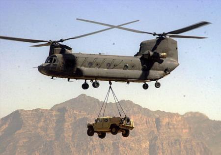 A CH-47D Chinook cargo helicopter lifts a Humvee vehicle at Bagram Air Base.