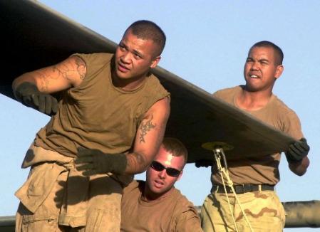 U.S. soldiers lift a 350 pound rotor blade to facilitate maintenance on the aft rotor head.