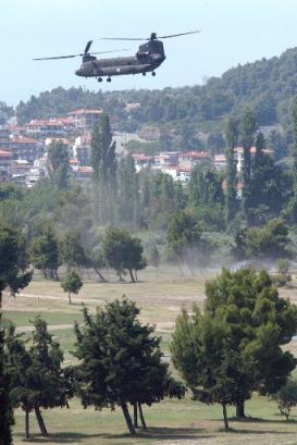 European Union (EU) delegation members arrive in a Greek Army Chinook helicopter as it hovers over the golf course of the Porto Carras Resort in Porto Carras, Greece. European leaders arrived at the heavily guarded coastal resort Thursday to start a three-day summit on illegal immigration. Seen in background is the town of Neos Marmaras.