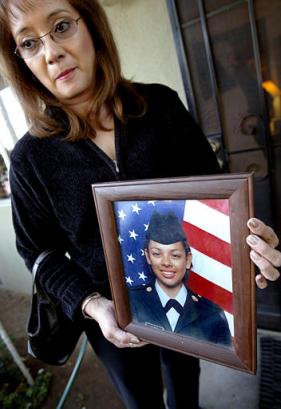 Isabel Jimenez of Sacramento, California, on Monday, 3 November 2003, stands outside of the Lau home in Livingston, California, holding a photo of her cousin Karina Lau, one of the 15 U.S. Army soldiers who died when their helicopter was shot down in Iraq on Sunday morning. Lau, 22, boarded a Chinook transport helicopter headed toward the Baghdad Airport, where she was scheduled to board an airplane to the United States for a two week surprise visit with her family in California.