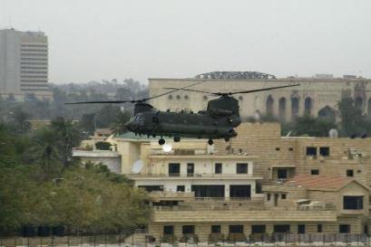 7 March 2004: A U.S. Army Special Forces Chinook helicopter hovers low above the Tigris River near the former Presidential Palace (background right) of ousted Iraqi dictator Saddam Hussein located at the "Green Zone" in Baghdad, Iraq, in the late afternoon on Sunday. Rockets were fired a few hours later towards the al-Rasheed Hotel (at left) in the heavily-fortified Green Zone - a base for Coalition forces and civilian personnel - on the eve of the again delayed historic signing of the new Interim Iraqi Constitution. The signing has been delayed twice before by rebel attacks around the country.