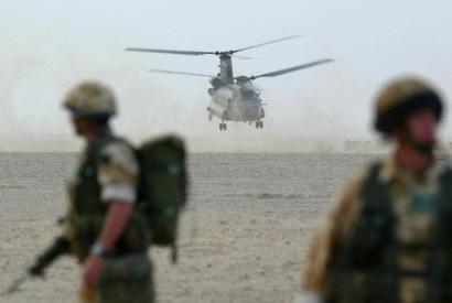 Soldiers of the British 1st Batallion Parachute Regiment look at a Chinook helicopter take off.