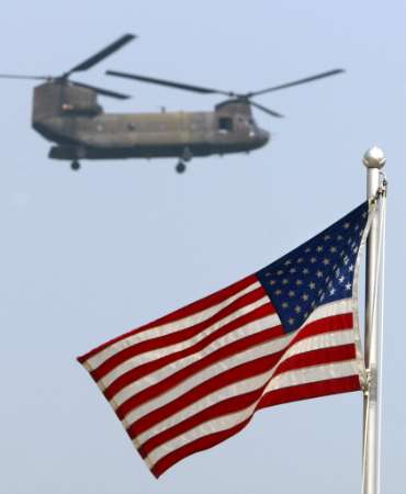 A U.S. Army Chinook helicopter carrying the USA soccer team members flies past a flag.
