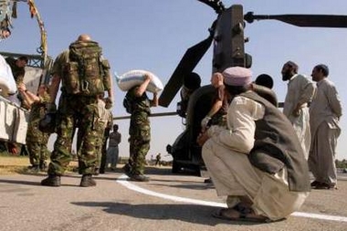 29 October 2005: In Islamabad, Pakistani men watch British troops load a Chinook helicopter with medical aid to be flown out to the more remote and effected areas within Pakistan. 27 Squadron Royal Air Force from RAF Odiham have provided three Chinook helicopters in which relief aid will be transported.