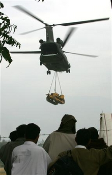 25 October 2005: Kashmiri earthquake survivors watch as a U.S. Chinook helicopter lifts a bulldozer from a makeshift heliport in Muzaffarabad. Senate and House negotiators on Tuesday agreed to a $20.9 billion foreign aid bill, with less than President George W. Bush wanted for reform-minded nations, and nearly $3 billion to fight AIDS.