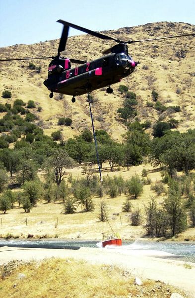 A California Army National Guard CH-47 Chinook helicopter wrenches a 660-gallon water bucket out of an aqueduct.