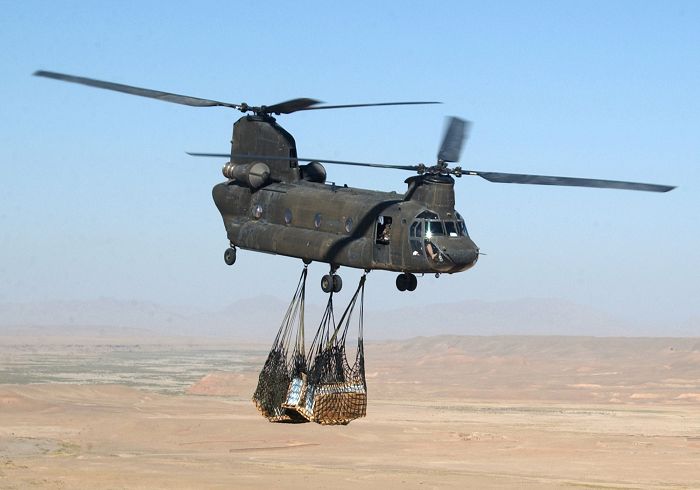 A CH-47D Chinook helicopter, tail number unknown, sling loads supplies via a cargo net to a Combined Medical Assistance camp site in Marouf Valley, Afghanistan. Soldiers of the 10th Mountain Division and members of other Army civil affairs and psychological operations units set up the camp to provide the villagers with medical care and distribute food supplies.